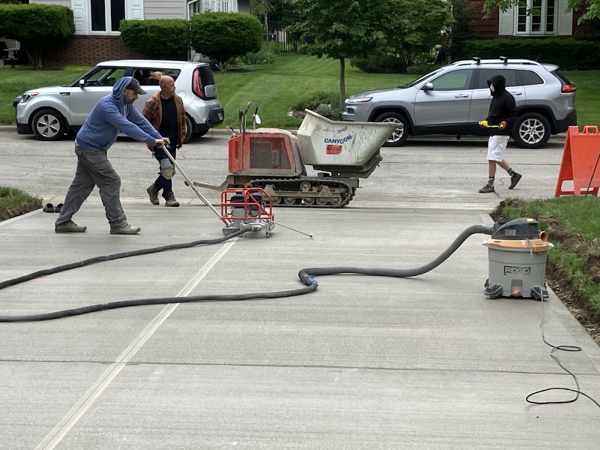 Crew cutting control joints into a fresh driveway pour